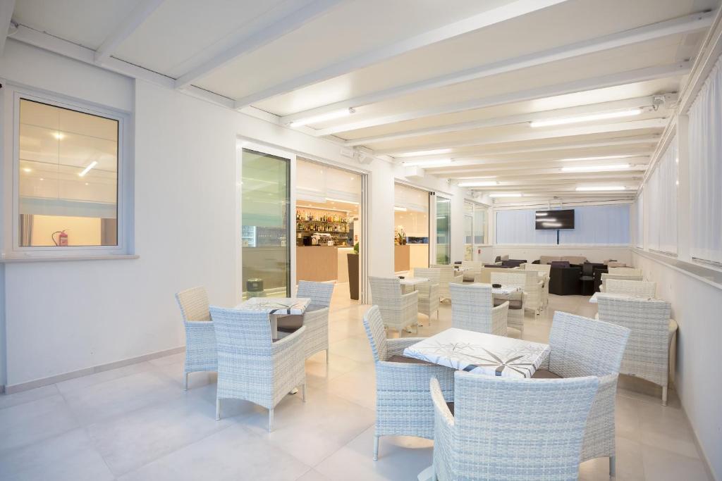 une salle à manger avec des tables et des chaises blanches dans l'établissement Hotel Montreal, à Bibione