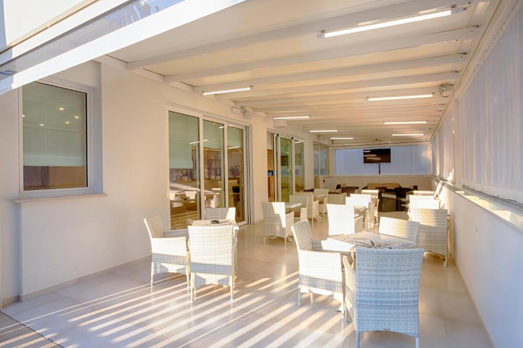 une salle à manger avec des chaises blanches et une table dans l'établissement Hotel Montreal, à Bibione