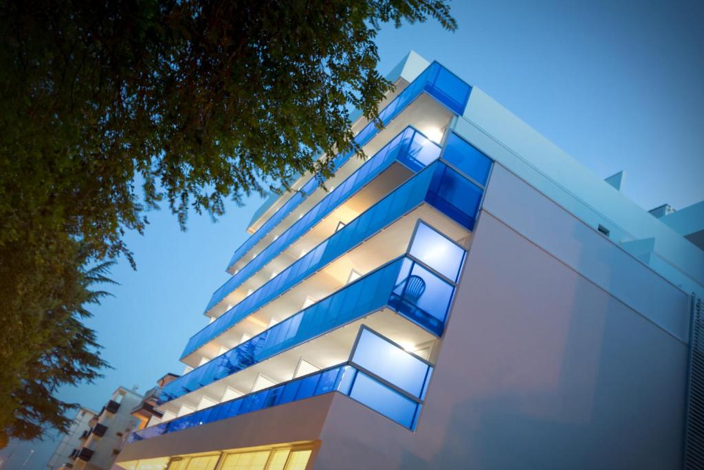 un immeuble avec des balcons bleus la nuit dans l'établissement Hotel Montreal, à Bibione