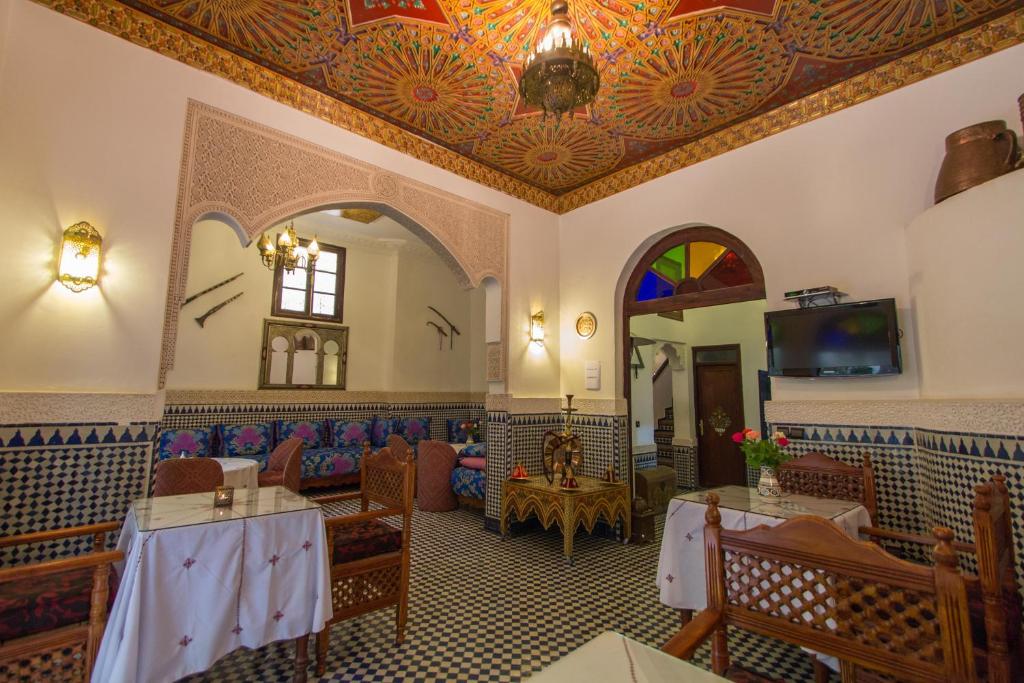 un restaurant avec des tables, un canapé et une télévision dans l'établissement Riad Jardin Chrifa, à Fès