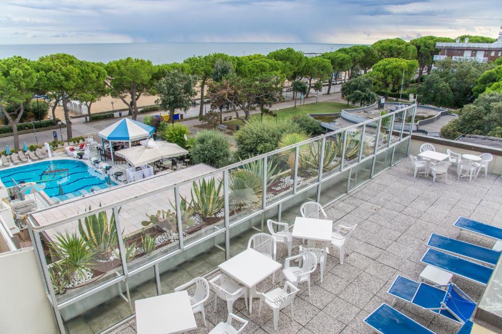 d'un balcon avec des tables et des chaises et une piscine. dans l'établissement Hotel Miramare, à Lignano Sabbiadoro