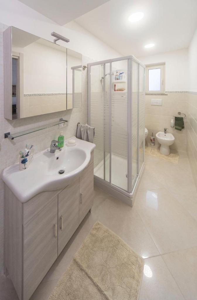 une salle de bain avec un lavabo, une douche et des toilettes dans l'établissement Casa Vacanza AcquaMarina, à Acireale