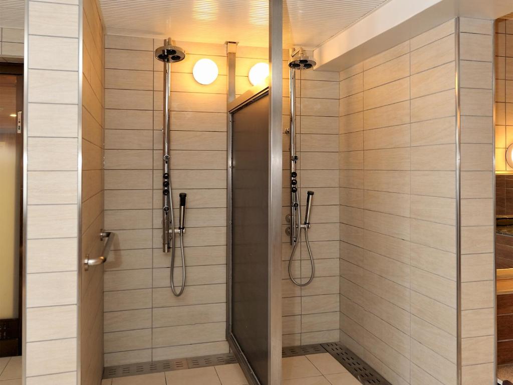une douche avec une porte vitrée dans une salle de bain dans l'établissement Shiga Park Hotel, à Yamanouchi