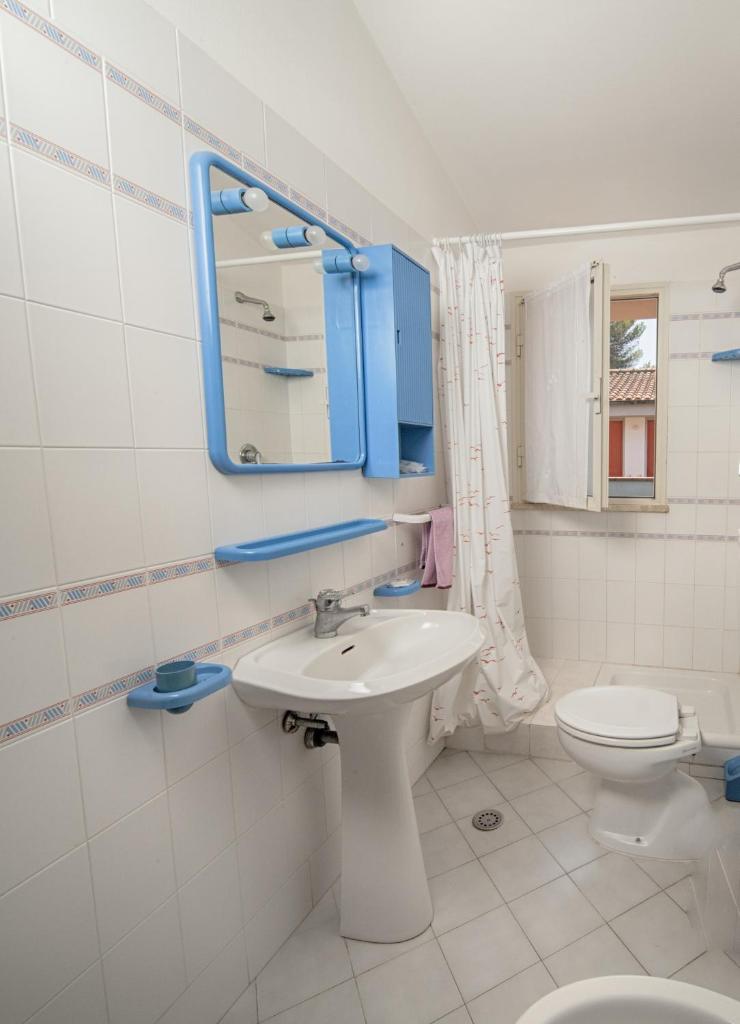 une salle de bain avec un lavabo, des toilettes et un miroir dans l'établissement Residence Airone, à Orbetello