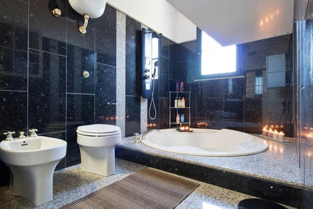 une salle de bain avec une baignoire, des toilettes et un lavabo dans l'établissement Villa Mariposa exclusive private pool, à Budoni