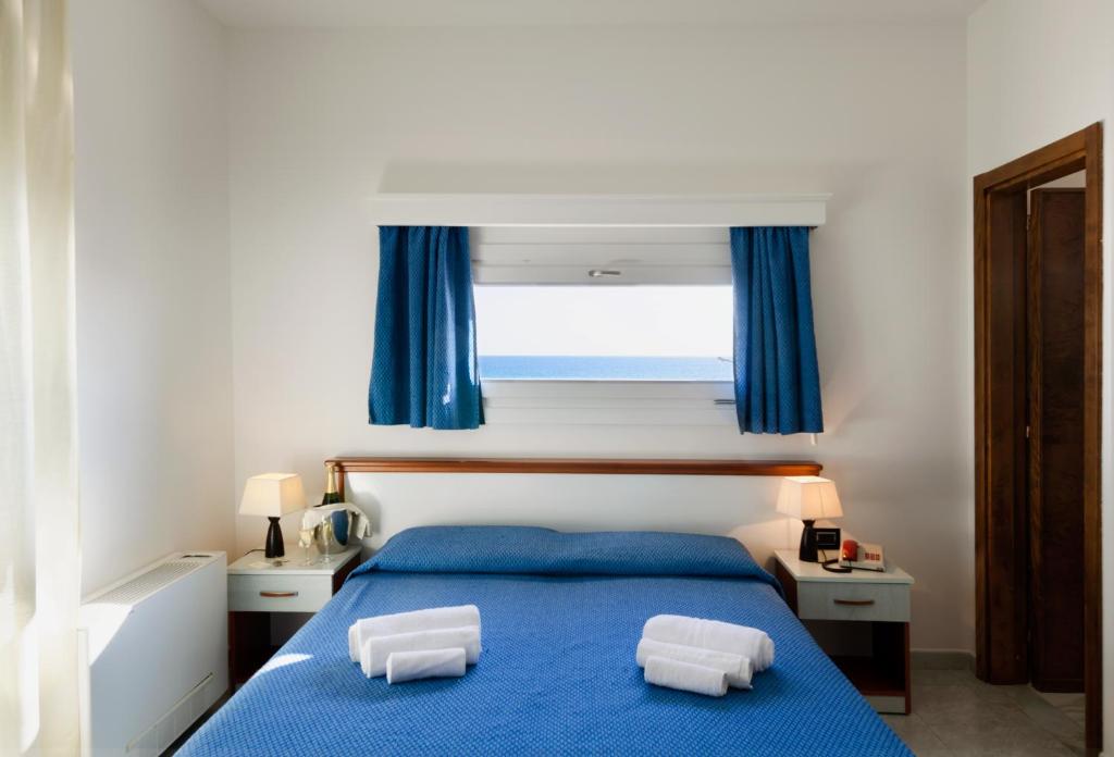 une chambre avec un lit bleu avec deux oreillers dessus dans l'établissement Hotel Luna Lido, à Torre San Giovanni
