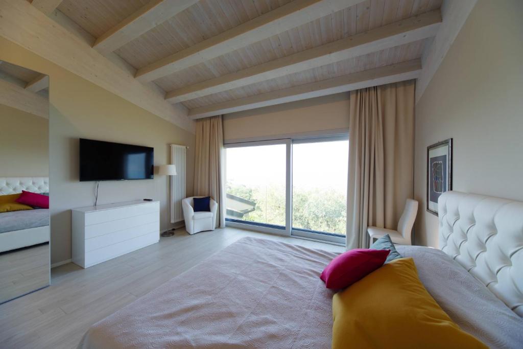 une chambre avec un grand lit et une grande fenêtre dans l'établissement Villa Elysium, à Torri del Benaco 41 autres photos