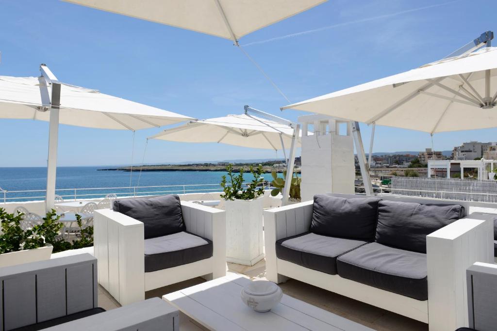 une terrasse avec 2 chaises et des parasols et l'océan dans l'établissement Hotel Don Ferrante, à Monopoli