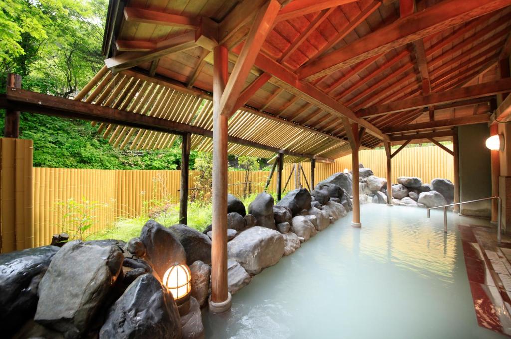 un bâtiment avec des rochers et un toit en bois dans l'établissement Park Hotel Miyabitei, à Noboribetsu
