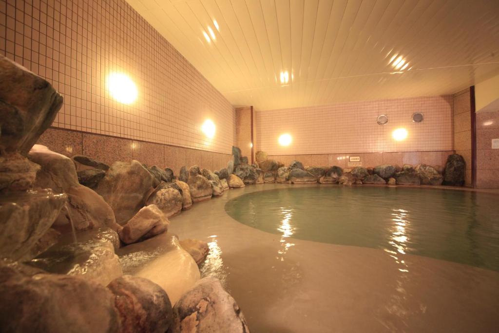 - une piscine d'eau avec des rochers dans une chambre dans l'établissement Park Hotel Miyabitei, à Noboribetsu