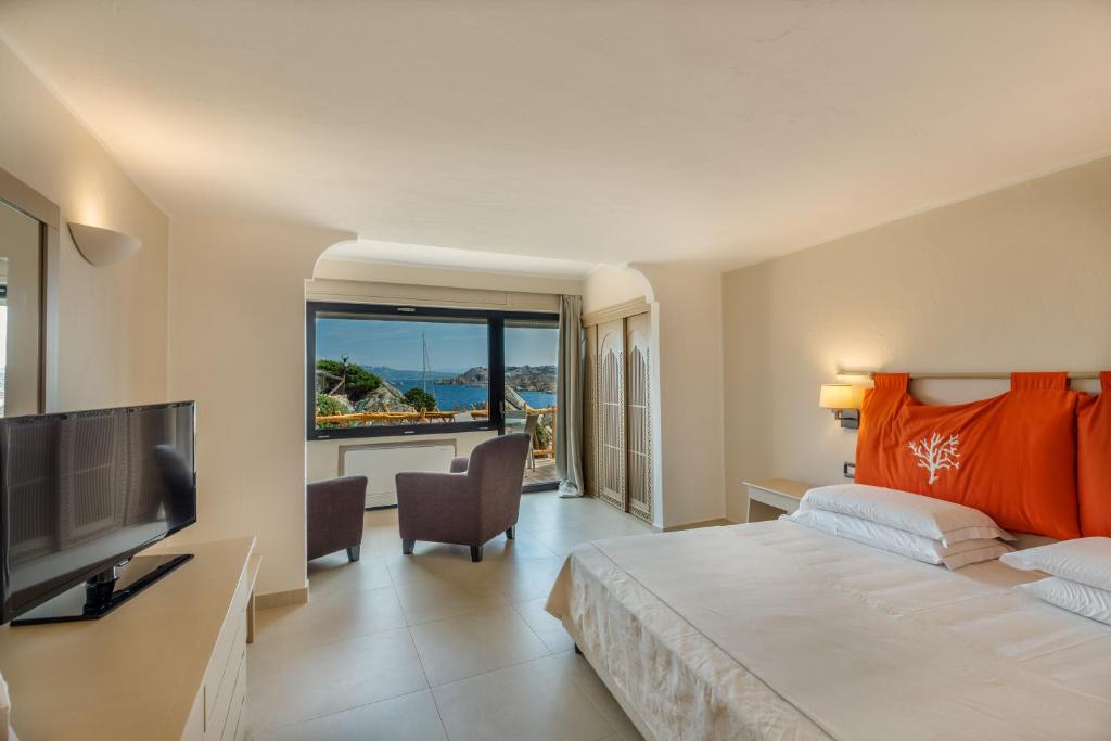 une chambre avec un grand lit et une grande fenêtre dans l'établissement Hotel Cala Lunga, à La Maddalena