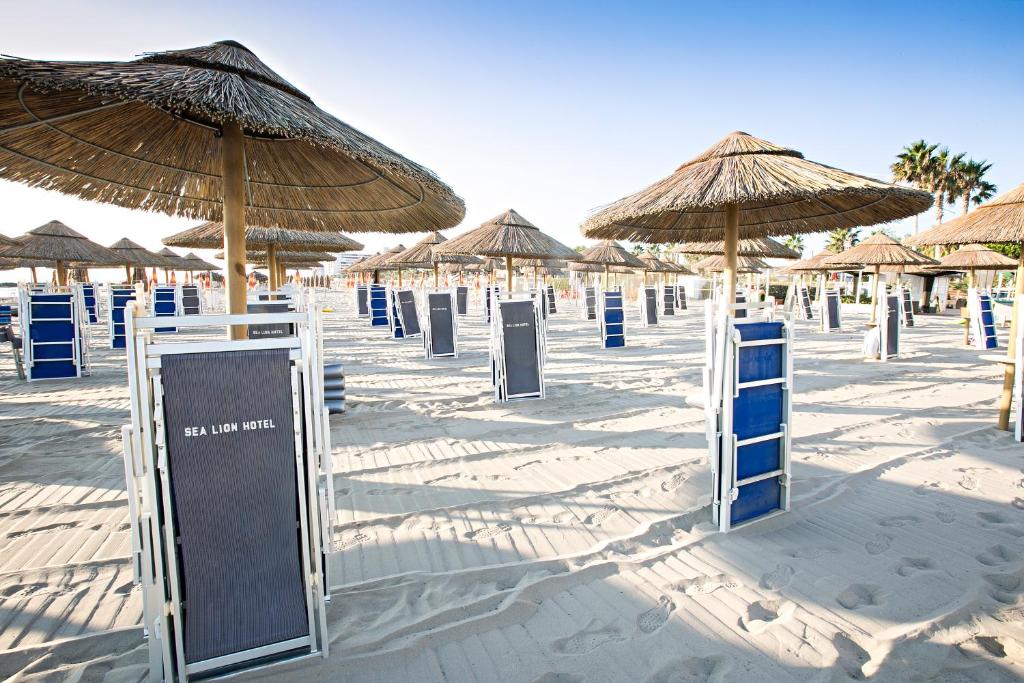 - une plage avec de nombreux parasols en paille et chaises bleues dans l'établissement Sea Lion Hotel, à Montesilvano