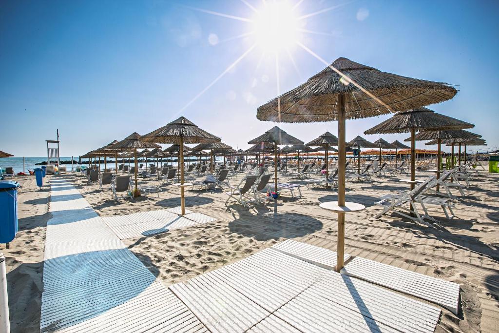- une plage avec de nombreux parasols et chaises en paille dans l'établissement Sea Lion Hotel, à Montesilvano