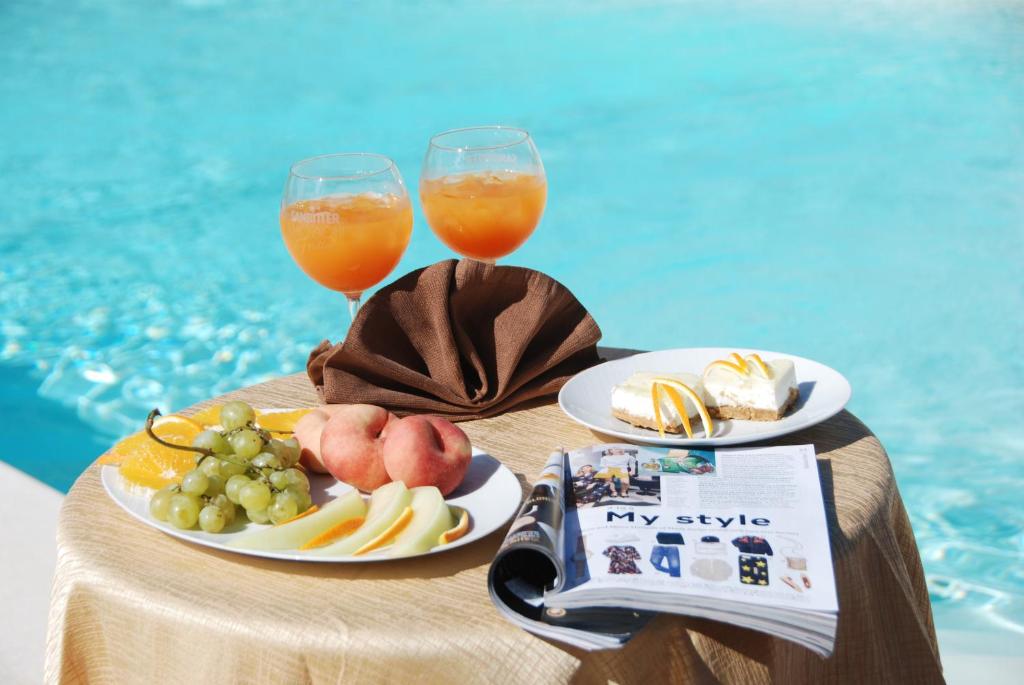 une table avec des assiettes de nourriture et deux verres de jus dans l'établissement Hotel Oasi da Paolo, à Castelluzzo