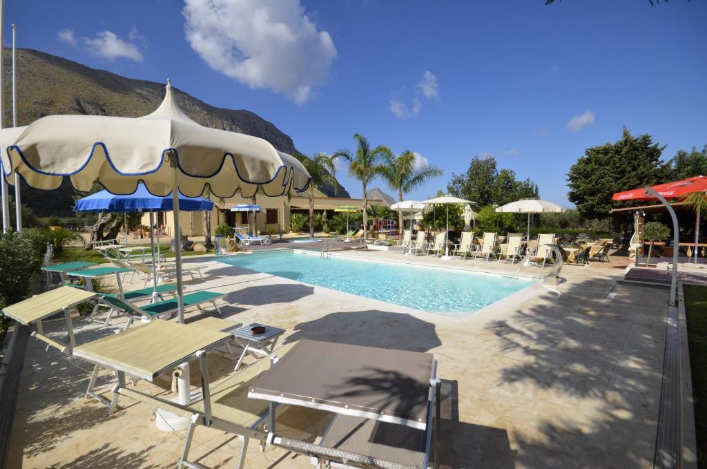 - une piscine avec des chaises longues et des parasols à côté d'un complexe dans l'établissement Hotel Oasi da Paolo, à Castelluzzo