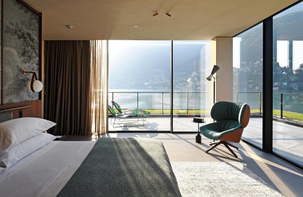 une chambre avec un lit et une chaise et un balcon dans l'établissement Il Sereno Lago di Como, à Torno