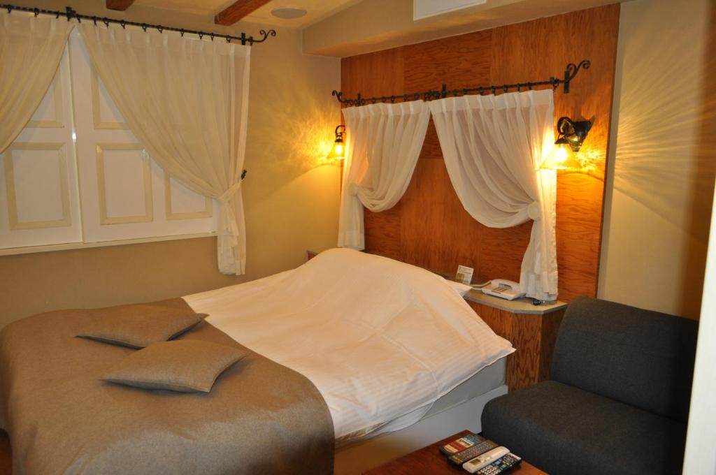 une chambre avec un lit, une chaise et une fenêtre dans l'établissement Hotel Woo (Adults Only), à Yamatotakada