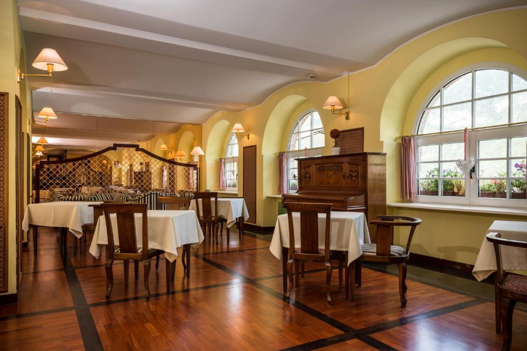 une salle à manger avec tables, chaises et fenêtres dans l'établissement Grand Hotel Molveno, à Molveno