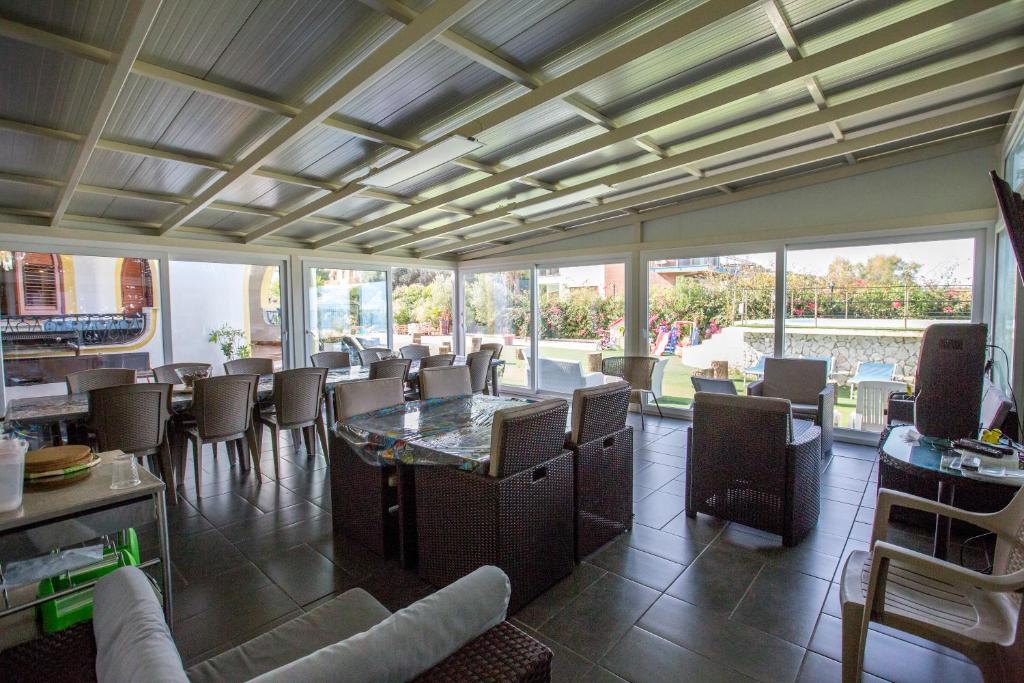 une salle à manger avec une table, des chaises et des fenêtres dans l'établissement Villa Silvia by Ville in Palermo, à Casteldaccia