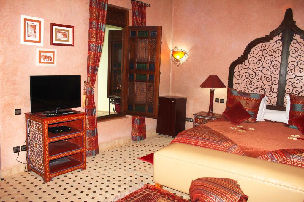 une chambre avec un lit et une télévision à écran plat dans l'établissement Riad Alida, à Marrakech