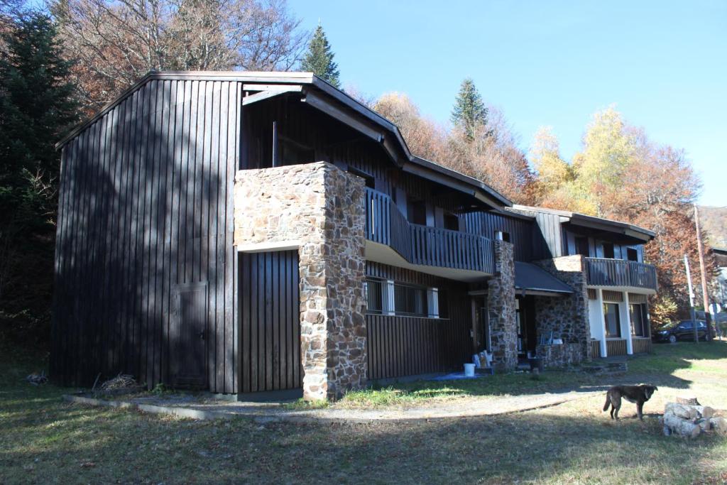 une maison avec un chien debout devant elle dans l'établissement Chalet Hotel Les Marmottes 2 étoiles NN, à Montferrier