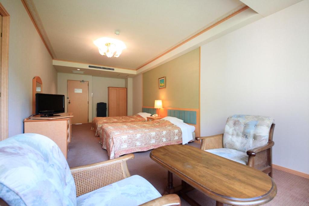 une chambre d'hôtel avec deux lits et une table dans l'établissement Park Hotel Miyabitei, à Noboribetsu