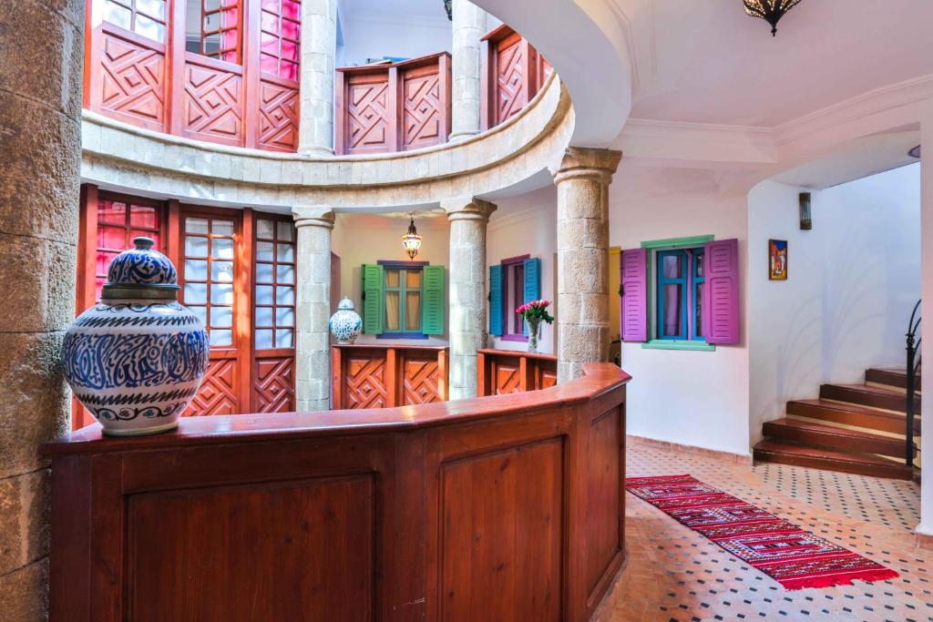 un vase sur une table dans une chambre avec des portes colorées dans l'établissement Riad Al khansaa, à Essaouira