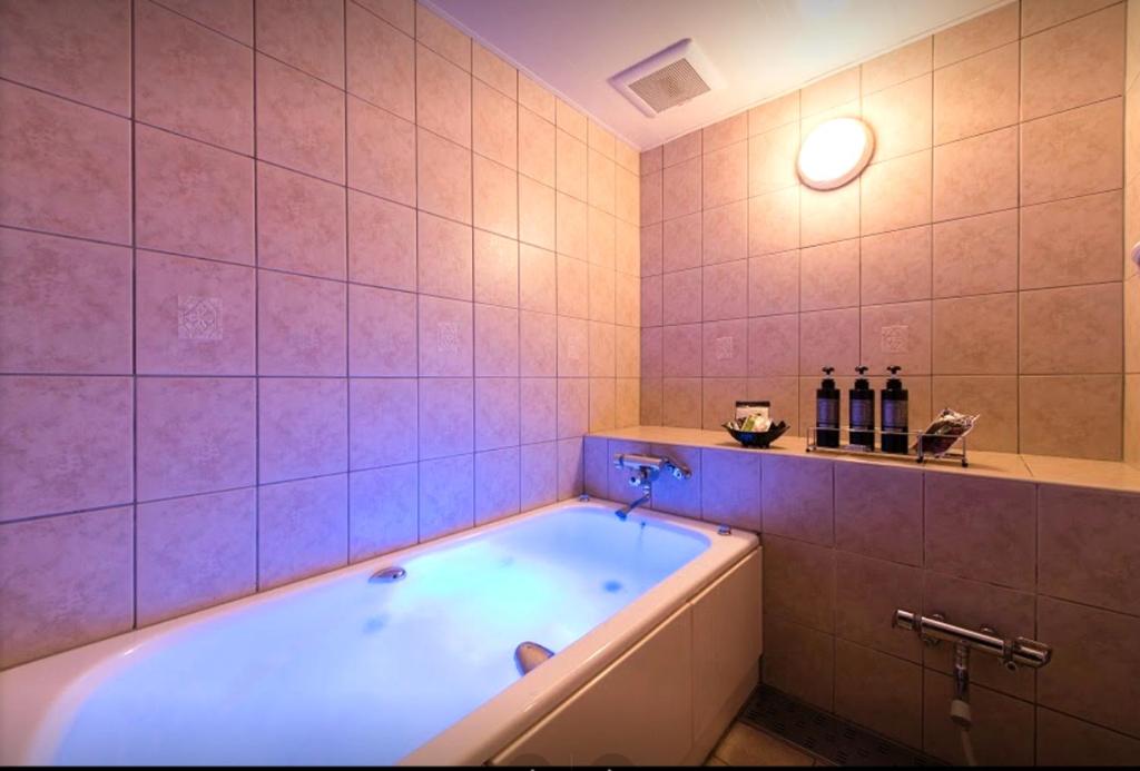 La salle de bains est pourvue d'une baignoire et de carrelage rose. dans l'établissement BAMBOO GARDEN Shinyokohama only Adult, à Yokohama