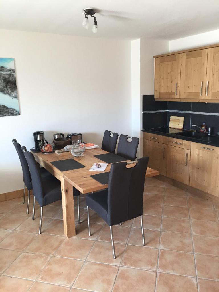 une cuisine avec une table en bois et des chaises noires dans l'établissement Les Saisies Bisanne, aux Saisies 29 autres photos