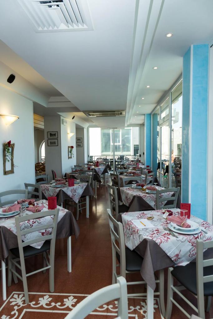 une salle à manger avec tables, chaises et fenêtres dans l'établissement Hotel Sayonara, à Cattolica