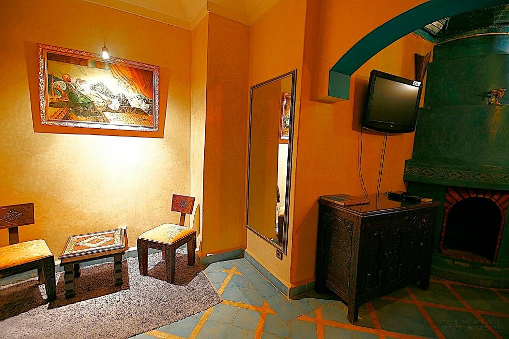un salon avec une cheminée et une télévision dans l'établissement Riad Mille Et Une Nuits, à Marrakech