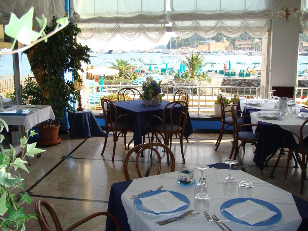 un restaurant avec des tables et des chaises et une grande fenêtre dans l'établissement Hotel Helios, à Santa Margherita Ligure