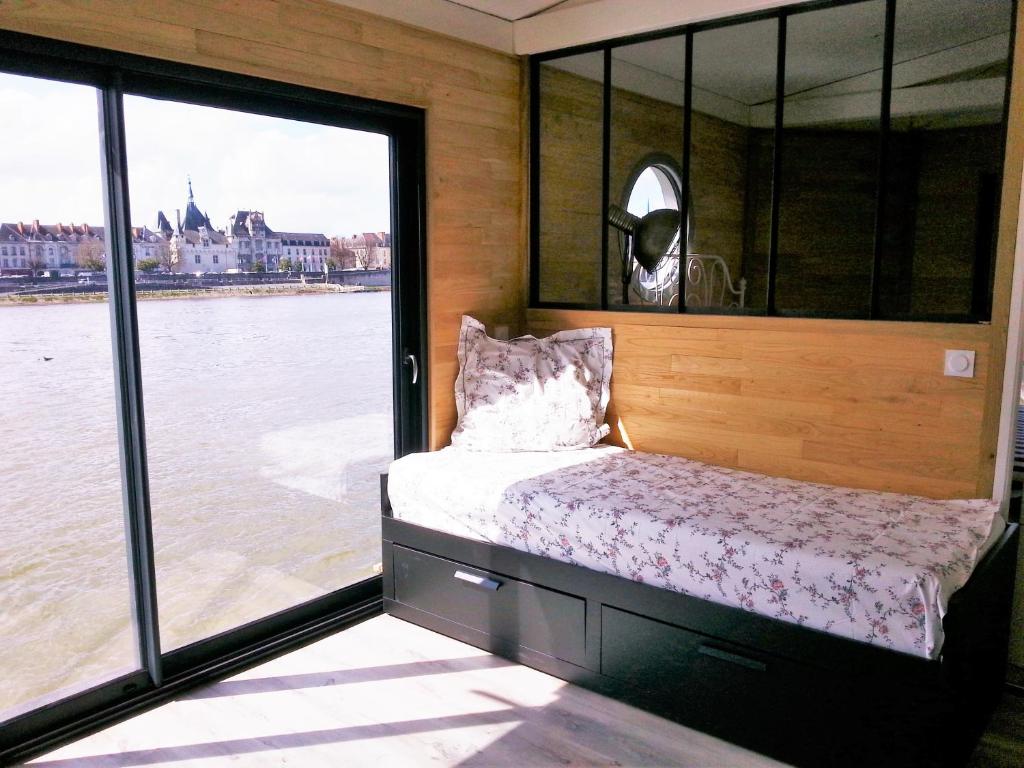 Ce lit se trouve dans un dortoir avec vue sur l'eau. dans l'établissement Different Holidays, à Saumur