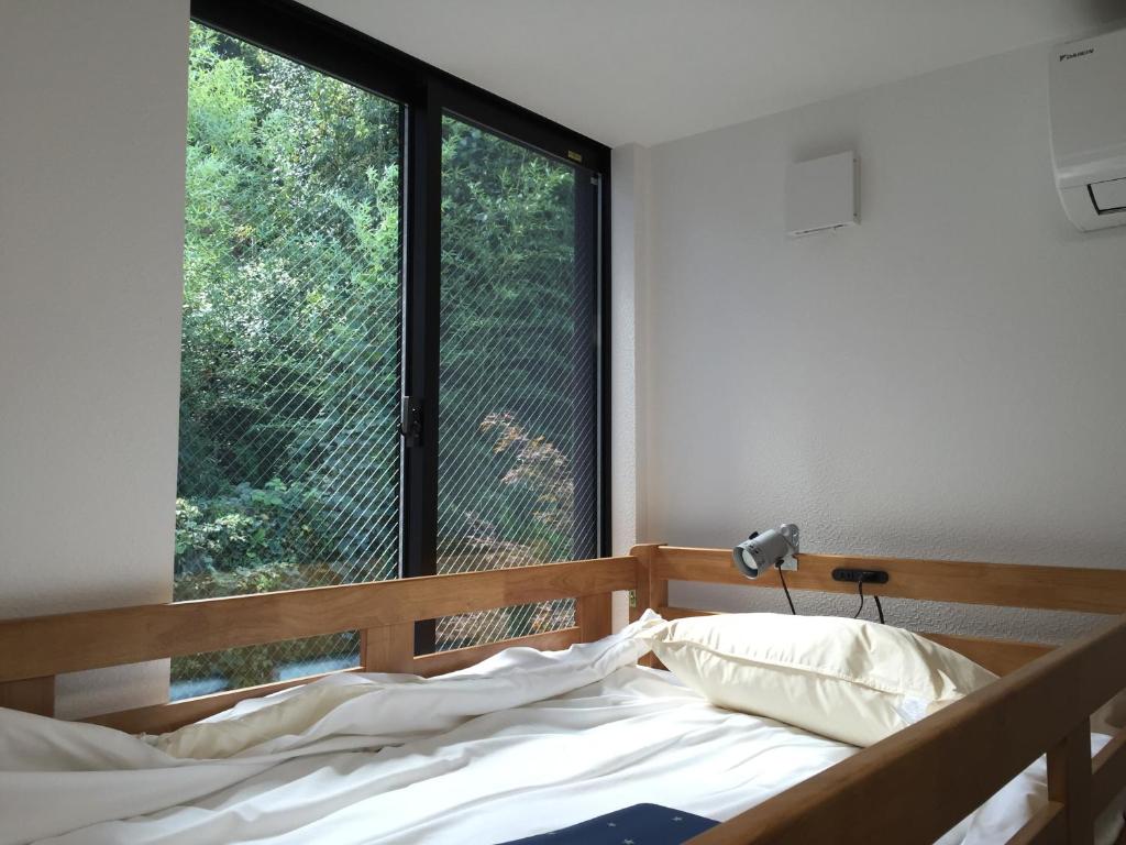 une chambre avec un lit et une grande fenêtre dans l'établissement add-Hostel Uji Cha-gan-ju-tei, à Uji