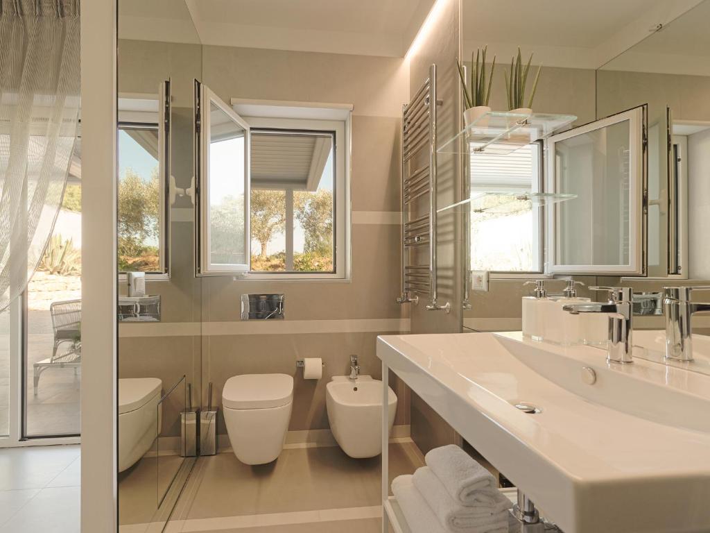 une salle de bain avec un lavabo et des toilettes et des fenêtres dans l'établissement Il Giardino degli Dei, à San Leone