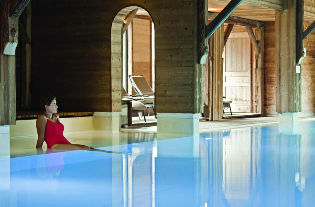 une femme assise au niveau de la piscine dans l'établissement Chalet-Hôtel La Marmotte, La Tapiaz & SPA, The Originals Relais, aux Gets