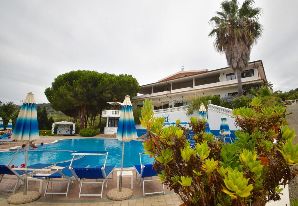 un complexe avec une piscine avec chaises longues et parasols dans l'établissement Villaggio Pineta Petto Bianco, à Capo Vaticano