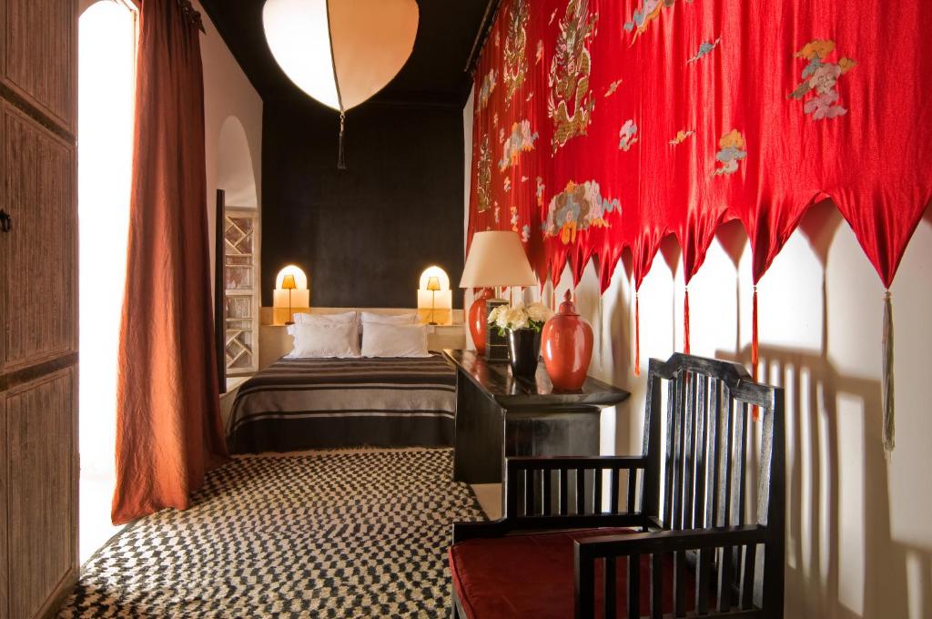 une chambre avec un lit et un rideau rouge dans l'établissement Riad Tzarra, à Marrakech