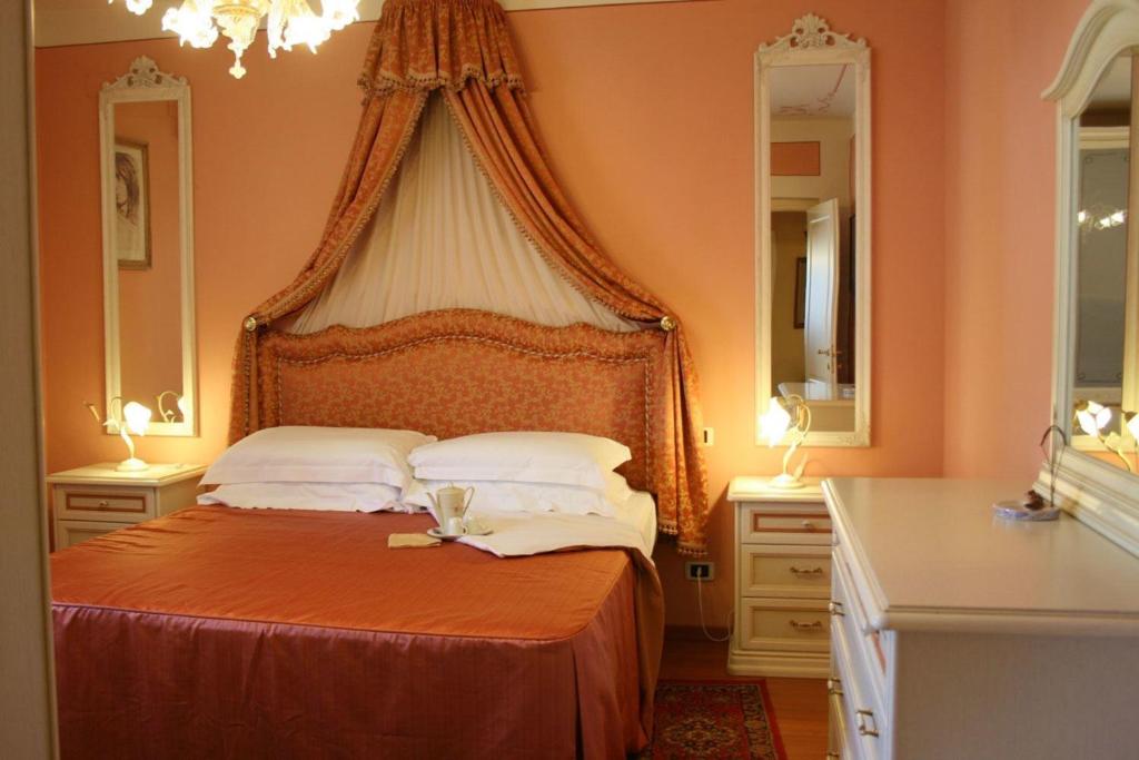 - une chambre avec un lit orange et deux miroirs dans l'établissement Villa Cappuccini, à Castiglion Fiorentino 22 autres photos