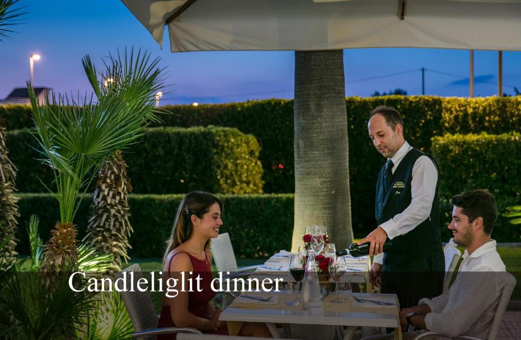 un groupe de personnes assises à une table avec un serveur dans l'établissement Hotel Olimpico, à Pontecagnano