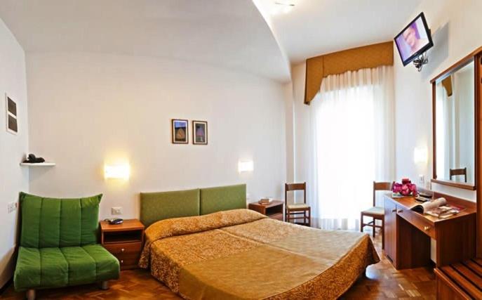 - une chambre avec un lit et une chaise verte dans l'établissement Hotel Gimm, à Bibione
