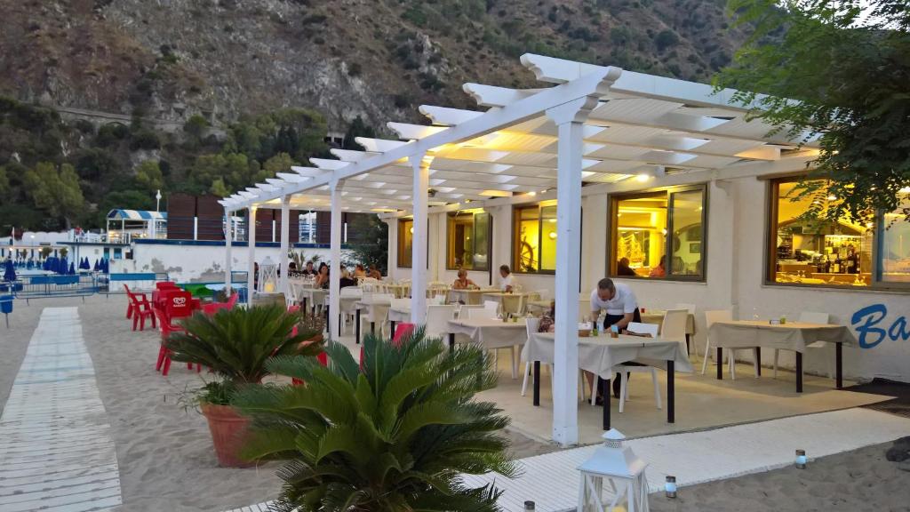 un restaurant avec des tables et des chaises blanches et des gens assis à des tables dans l'établissement Il Gabbiano, à Stalettì