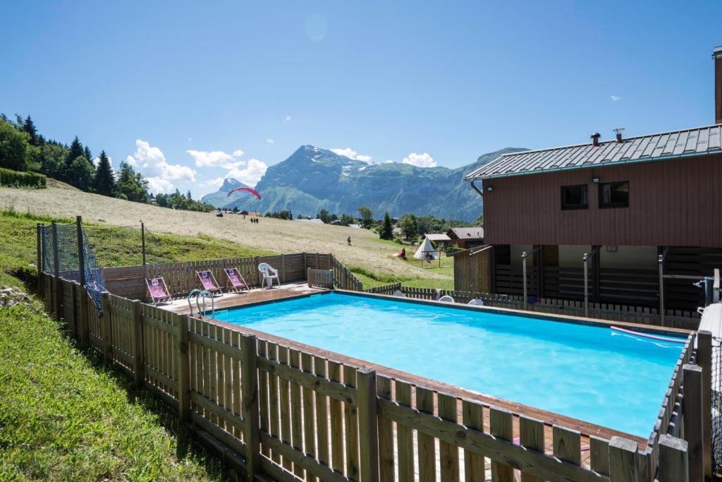 - une piscine sur une colline à côté d'une maison dans l'établissement Village De Vacances Les Flocons Verts, aux Carroz d'Arâches