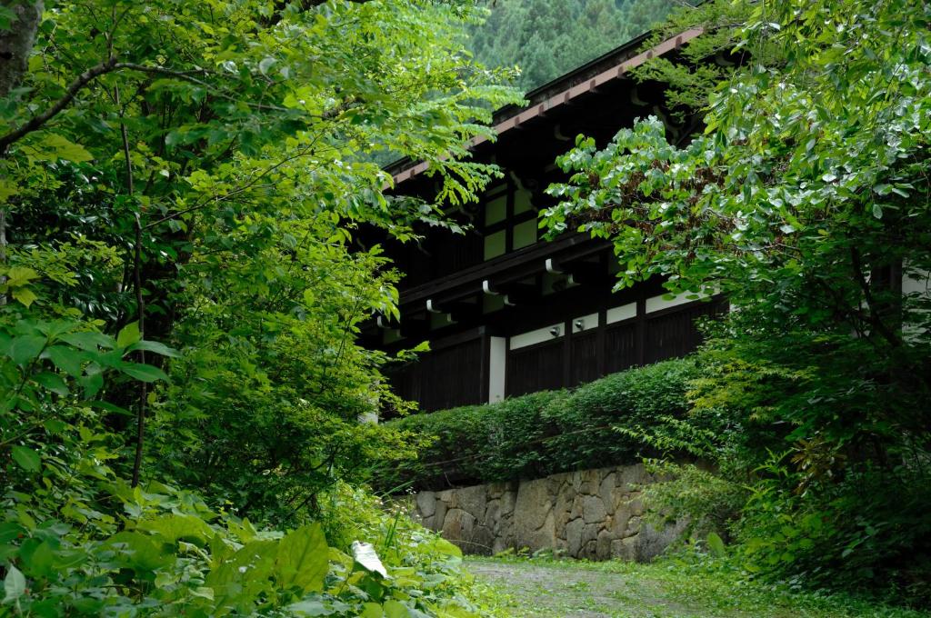 un bâtiment entouré d'arbres et d'un mur en pierre dans l'établissement Yumoto Choza, à Takayama