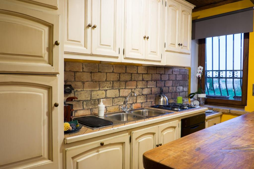 La cuisine est équipée de placards blancs, d'un évier et d'un comptoir. dans l'établissement Villa Nadia, with an exclusive swimming pool, à Monterosi