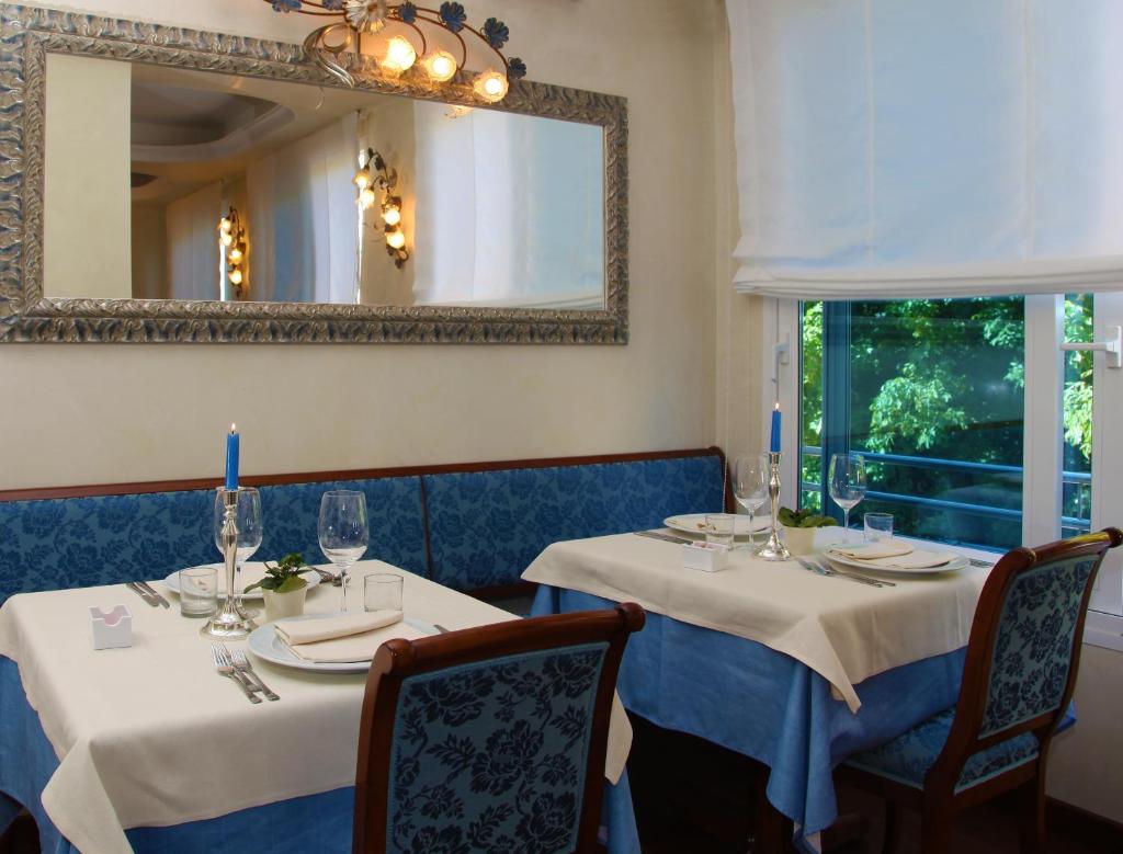 une salle à manger avec deux tables et un miroir dans l'établissement Hotel Helios, à Lido di Jesolo 36 autres photos