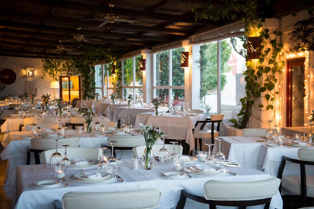 une salle à manger avec des tables et des chaises blanches dans l'établissement Masseria Torre Coccaro, à Savelletri di Fasano
