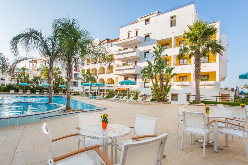 un patio avec des tables et des chaises à côté d'une piscine dans l'établissement Forte Hotel, à Vieste