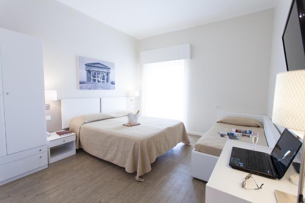une chambre avec un lit et un bureau avec un ordinateur portable dans l'établissement Hotel Costazzurra Museum & Spa, à San Leone
