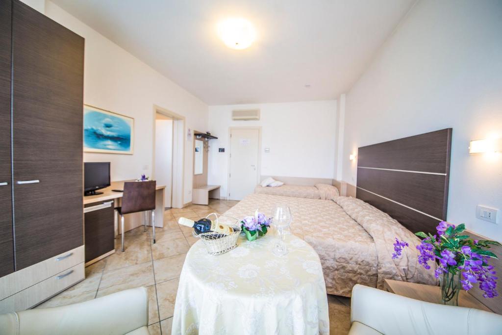 une chambre avec un lit et une table avec des fleurs dessus dans l'établissement Renzo Hotel, à Cesenatico